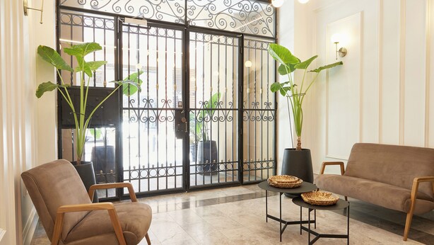Un interno moderno con una poltrona, una chaise longue e un cancello metallico decorativo.