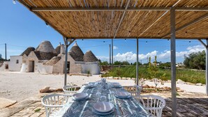 A table set outdoors with a view of unique conical-roofed buildings in the background. - 4003 Brunaldi Trulli by Perle di Puglia (Martina Franca)