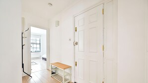 A hallway with a white door, a wooden bench, and a radiator.