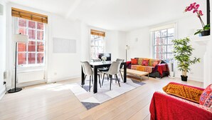 A bright living room with a dining area, large windows, and a red sofa.