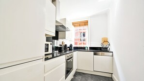 A compact kitchen with white cabinetry, a black countertop, and a built-in oven.