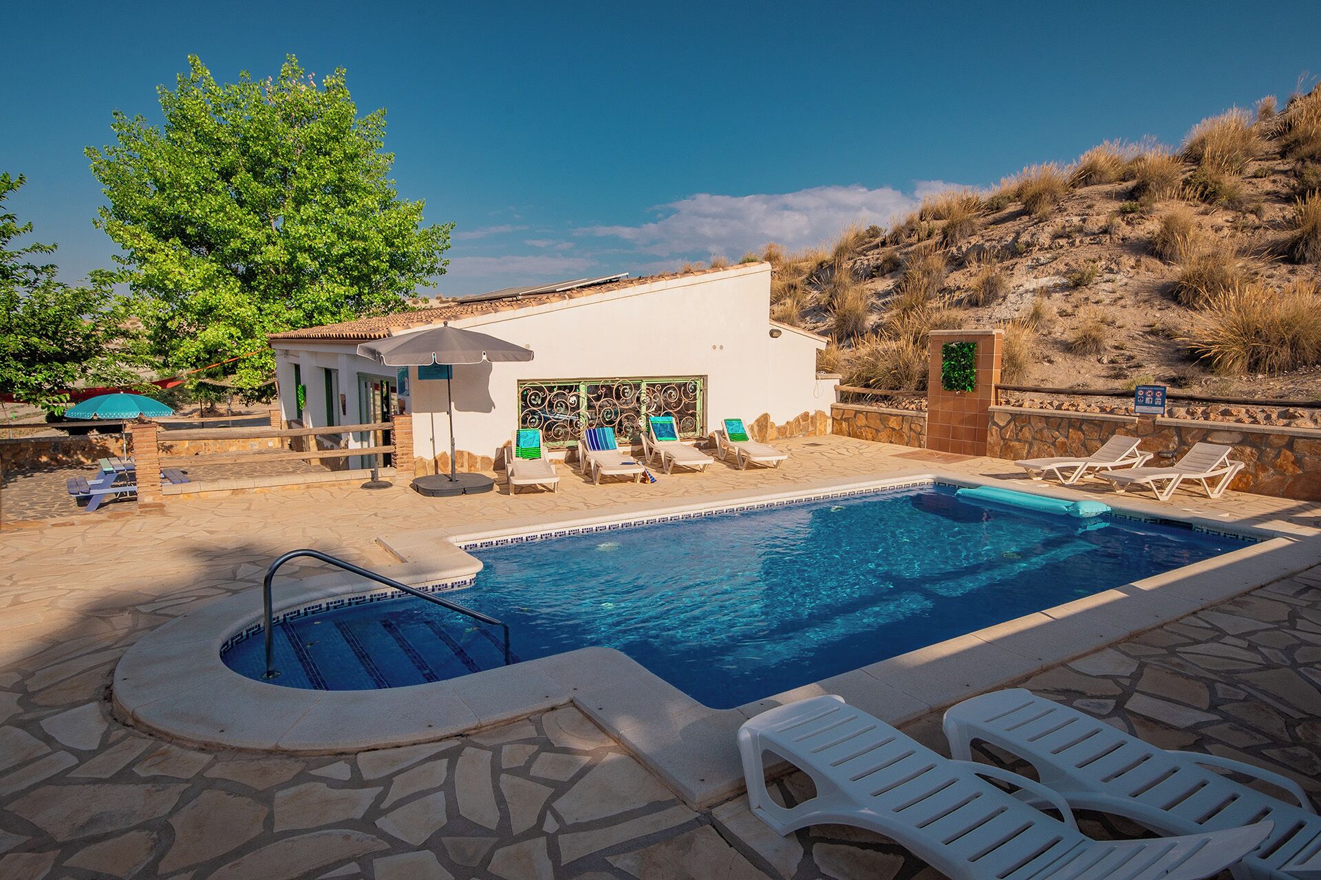 A swimming pool with lounge chairs and a small building with a decorative wall.