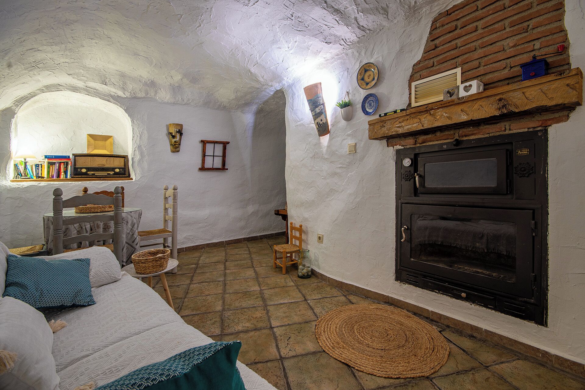 A rustic room with a fireplace, a wooden chair, a small table, and a bookshelf.