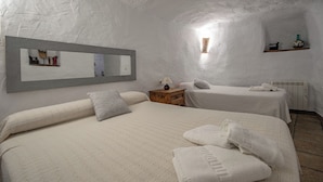 Een kamer met twee bedden, een nachtkastje, een spiegel en een plank met spullen.