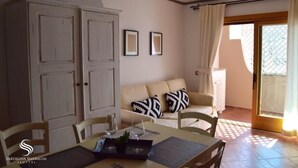 Un comedor con una mesa lista para dos, un sofá con cojines estampados y un mueble aparador grande.