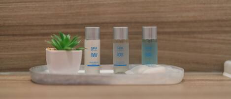 A tray with three spa products and a small plant on a wooden surface.