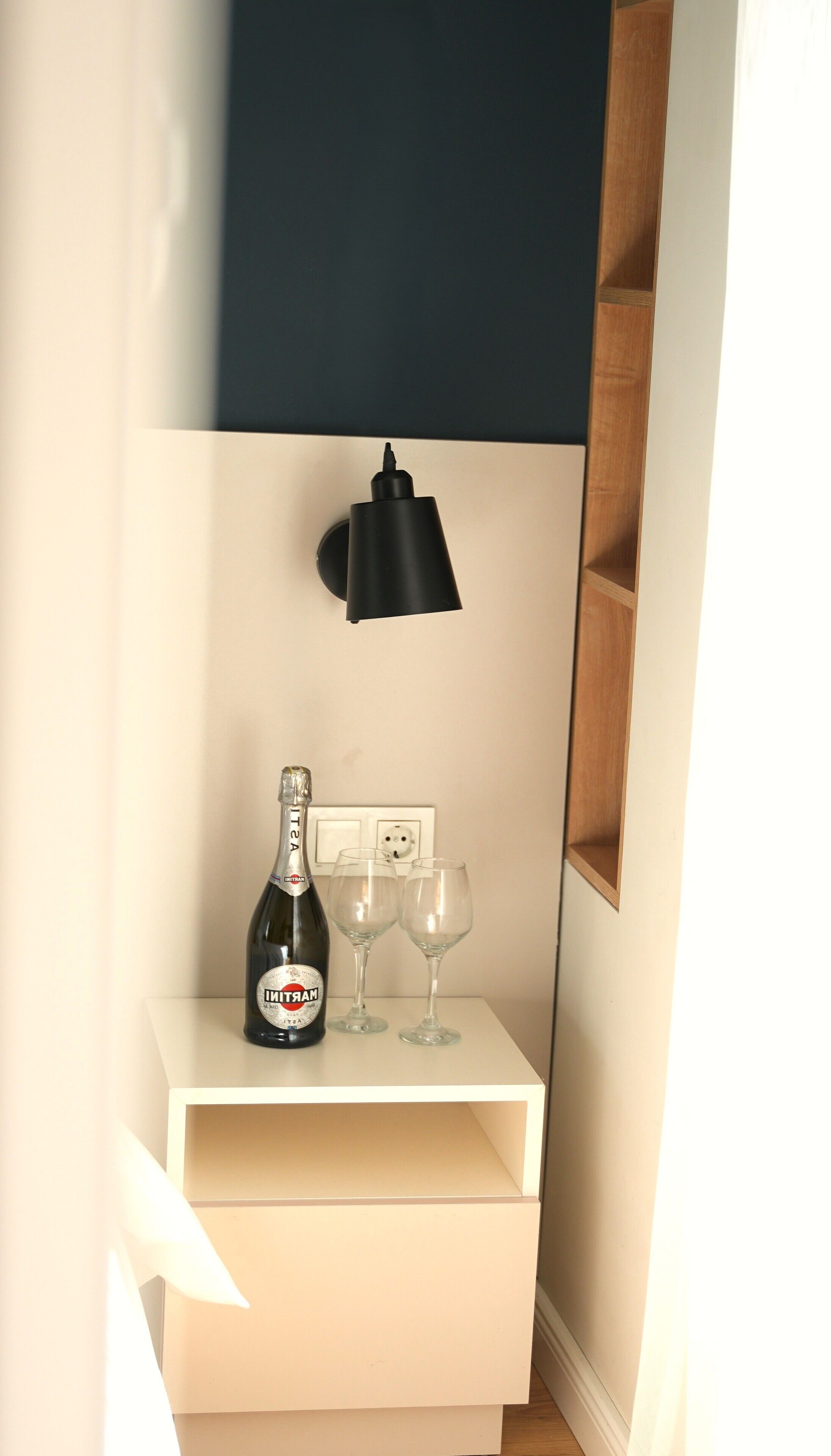 Una mesita de noche blanca con una botella de champán y dos copas.