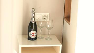 Una mesita de noche blanca con una botella de champán y dos copas.