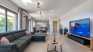 Ein modernes Wohnzimmer mit einer Eckcouch, einem runden Couchtisch und einem großen Flachbildfernseher.