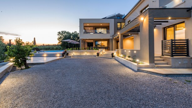 Ein modernes Haus mit Kiesweg, Sitzgelegenheit im Freien und einem Pool.