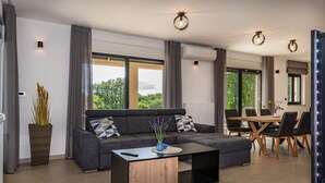 Ein modernes Wohnzimmer mit einer Eckcouch, einem Couchtisch und einem Essbereich mit einem Holztisch und Stühlen.