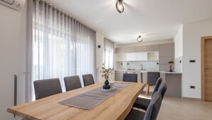 Eine moderne Küche mit weißen Schränken, einem Holztisch und einer Vase mit getrockneten Blumen.
