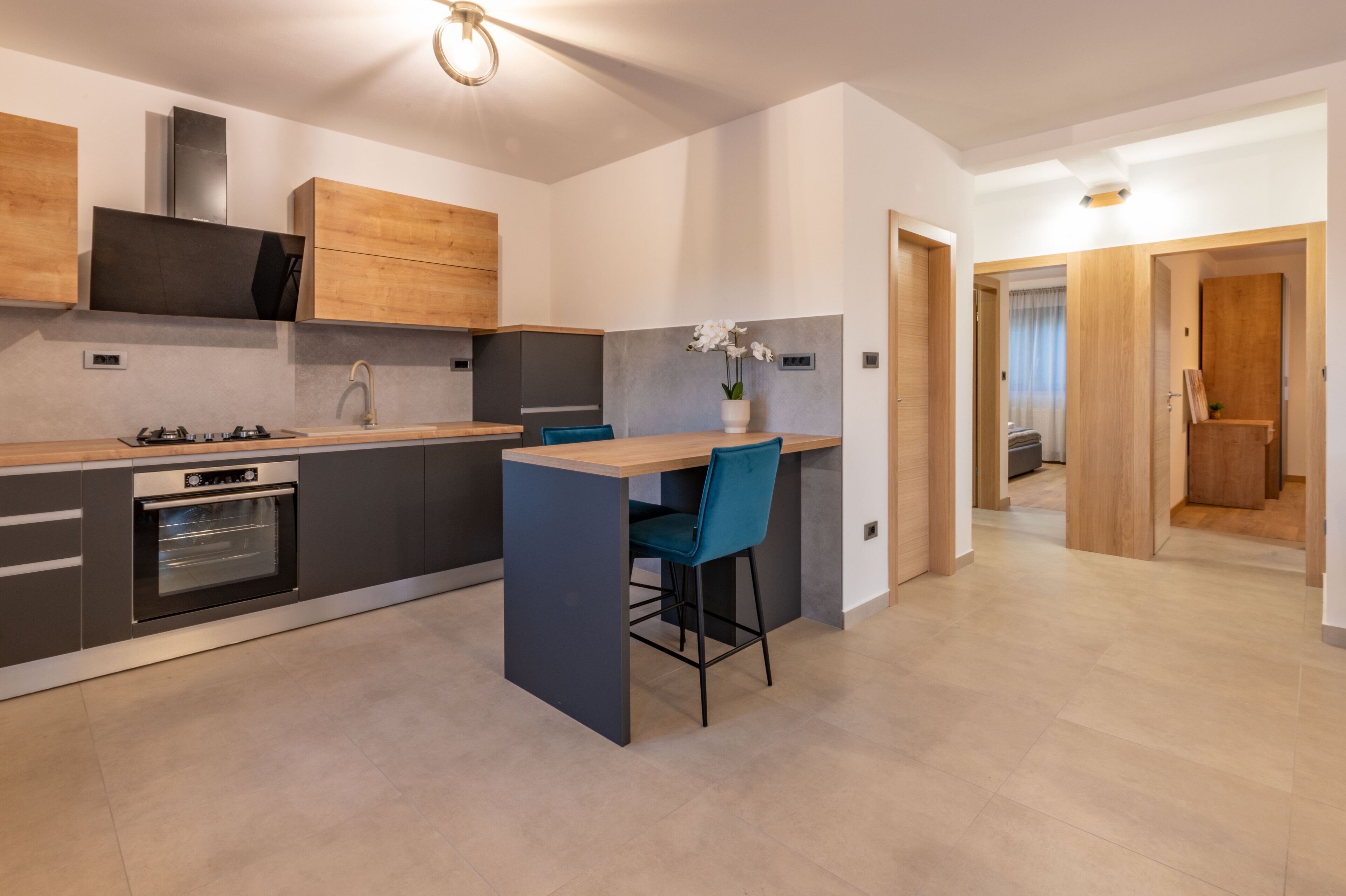 A modern kitchen with a central island, built-in oven, and wooden cabinets.