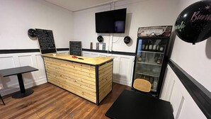 Une petite cuisine moderne, avec un comptoir en bois, un téléviseur noir fixé au mur et un distributeur de boissons.