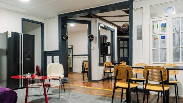Un espace repas moderne, avec un mélange de meubles en bois et de meubles rembourrés, un extincteur et un détecteur d’incendie bien visible.