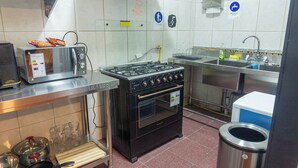 Une cuisine équipée d’une cuisinière à gaz, d’un four, d’un four à micro-ondes, d’un évier et de divers ustensiles de cuisine.