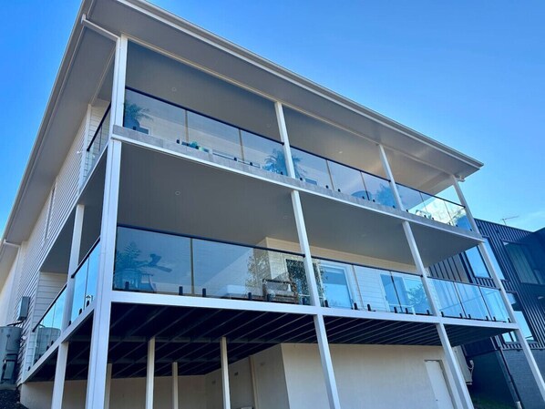 A modern multi-story building with large glass windows and balconies. - House on the hill | Kangaroo lookout (Wodonga)