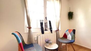 Una habitación con dos sillas coloridas, una mesita redonda con un florero y un radiador.