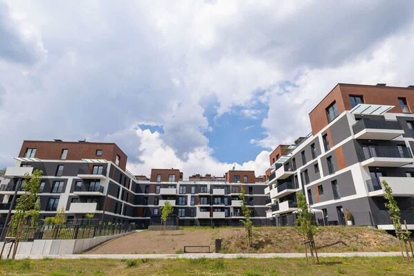 Un moderno complejo de apartamentos con varios edificios, balcones y un patio central.