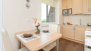A modern kitchen with wooden cabinets, a microwave, and a dining area with a table set for two.
