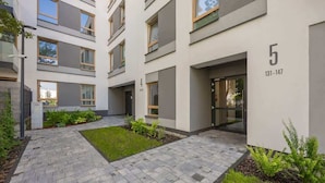 Un immeuble d’appartements moderne doté d’une cour pavée, portant le numéro 5, et dont l’entrée est bien visible.