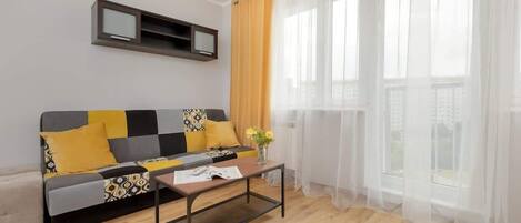A modern living room with a sofa, a coffee table, and a TV mounted on the wall.