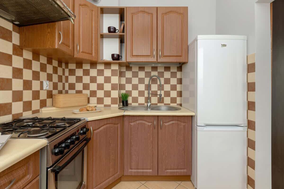 A kitchen with wooden cabinets, a gas stove, a sink, and a white refrigerator.
