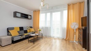 Una sala de estar moderna con un sofá, una mesa de centro y un ventilador de pie.