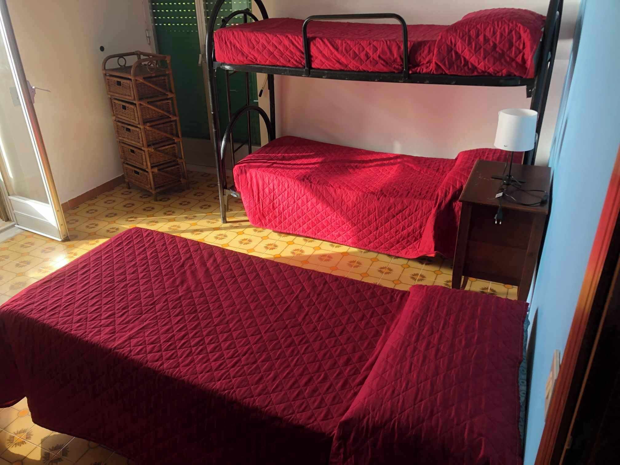 A dormitory room with two bunk beds, a small table with a lamp, and a wicker basket.