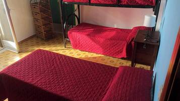 A dormitory room with two bunk beds, a small table with a lamp, and a wicker basket.