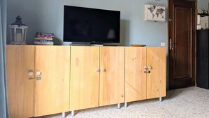 Habitació amb televisió sobre un moble de fusta, una porta i un llum penjant a la paret.