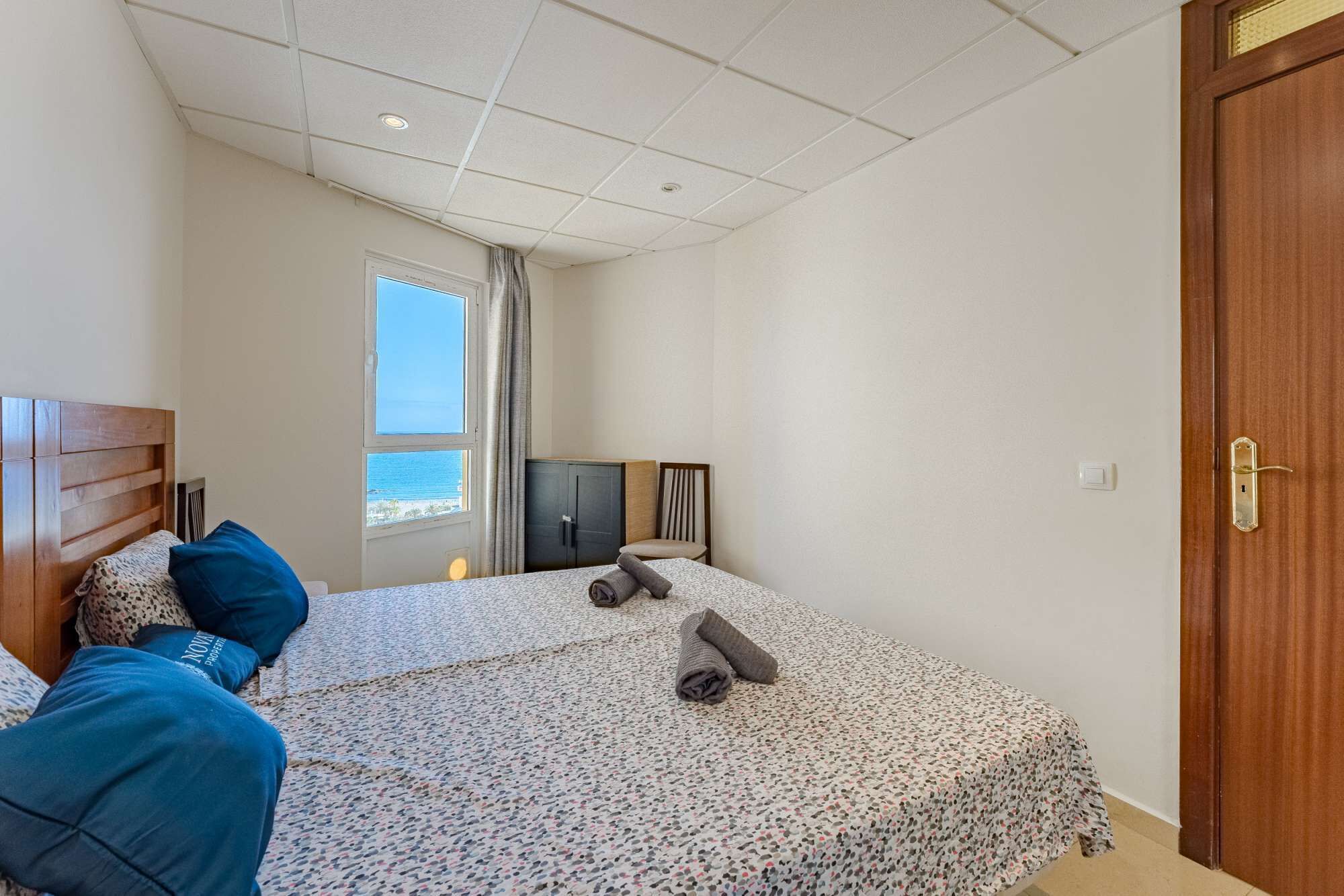 A bedroom with a bed, a TV, a wardrobe, and a window with a view.