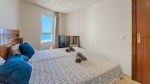 A bedroom with a bed, a TV, a wardrobe, and a window with a view. - Las Americas Ocean view Sunsets (Arona)