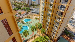 A high-rise building with multiple balconies, a rooftop pool area, and surrounding greenery. - Las Americas Ocean view Sunsets (Arona)