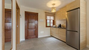 A kitchen with wooden cabinets, a stainless steel refrigerator, and a window with a view of greenery.