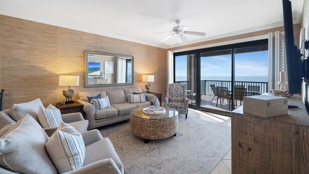 A spacious living room with a large window, a ceiling fan, and a balcony with a view. - Romar House 505B by Liquid Life (Orange Beach)