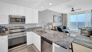 A modern kitchen with white cabinets, stainless steel appliances, and a granite countertop. - Lighthouse 810 by Liquid Life (Gulf Shores)