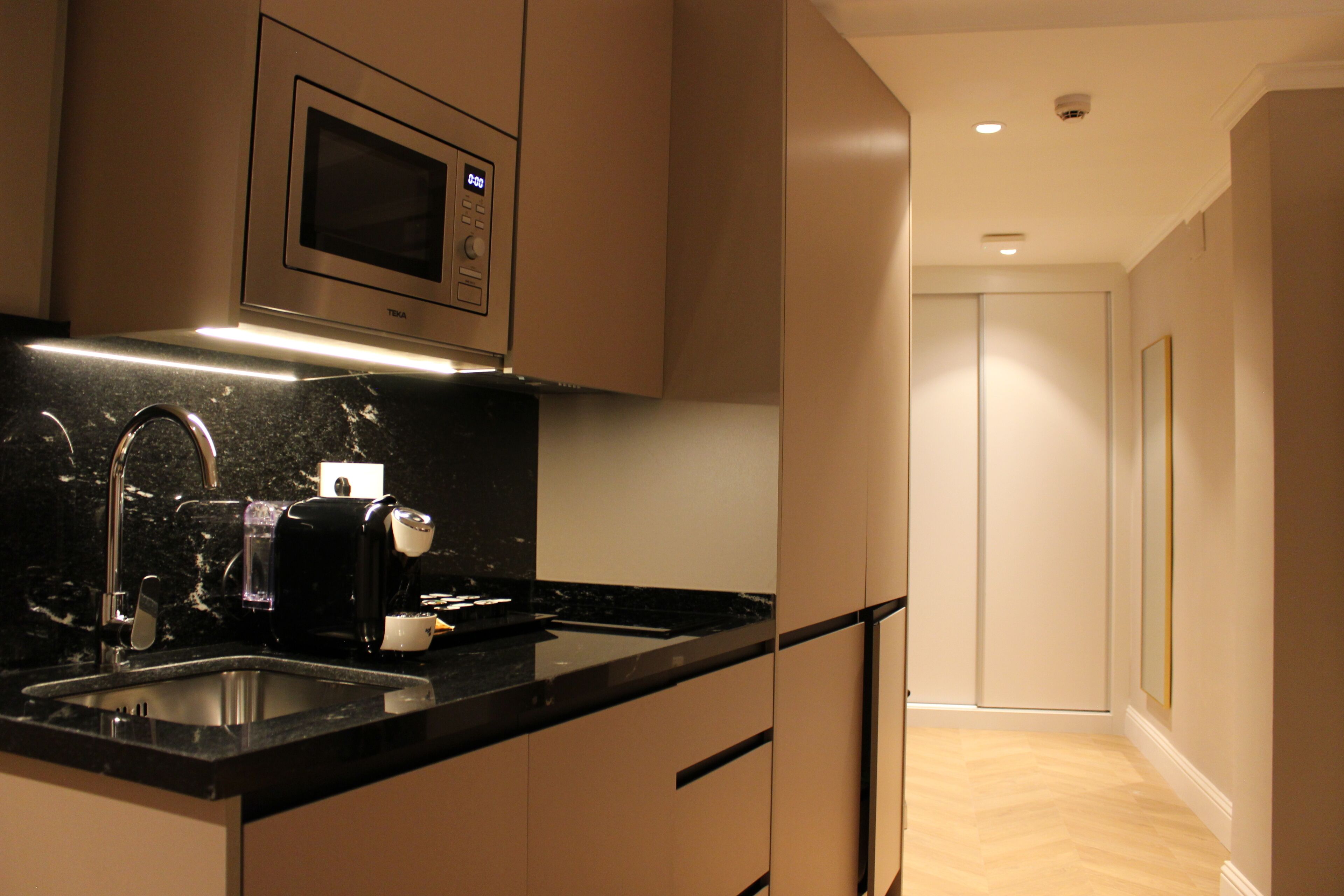 A modern kitchen with a built-in microwave, a coffee machine, and a sink.