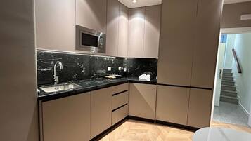 Una cocina moderna con encimera de mármol negro, electrodomésticos de acero inoxidable y suelo de madera.