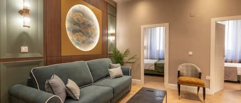 A modern living room with a green sofa, a small table, and a decorative wall piece.