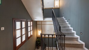 Una escalera con una pared oscura y una zona de descanso de color claro.