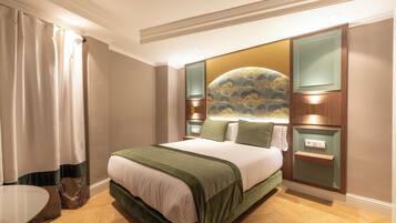 Habitación de hotel con una cama grande, una mesita de noche, un estante en la pared y una ventana con cortinas.