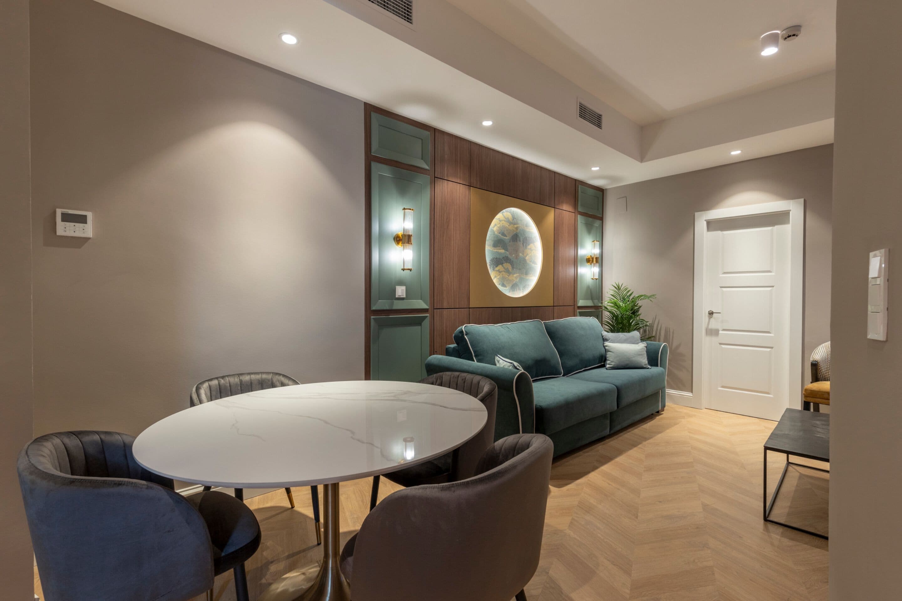 A modern living room with a round glass table, two sofas, and a coffee table.