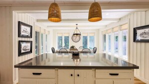 A kitchen with a central island, pendant lights, framed pictures, and a view of the outdoors through large windows. - Huron Shores, Hot Tub, Lakefront (Point Clark)
