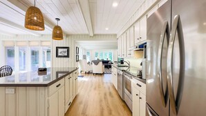A modern kitchen with white cabinetry, a stainless steel refrigerator, and pendant lighting. - Huron Shores, Hot Tub, Lakefront (Point Clark)