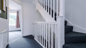 A staircase with white railings leading to a landing, carpeted stairs, and a door leading to an outdoor area. - Lovely 4 Bed Litherland Apartment (Liverpool)