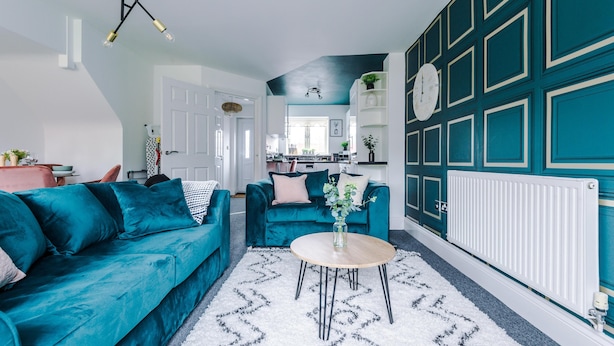A modern living room with teal sofas, a round coffee table, and a white rug. - Lovely 4 Bed Litherland Apartment (Liverpool)