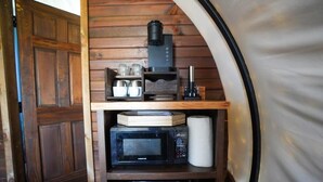 Un espace cuisine compact comprenant un four à micro-ondes, une machine à café et des étagères de rangement.