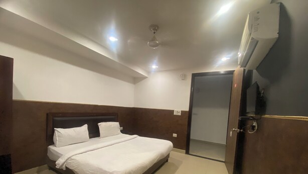 Une chambre d’hôtel équipée d’un lit, d’un ventilateur de plafond, d’un appareil de climatisation et d’une porte donnant sur une autre pièce.
