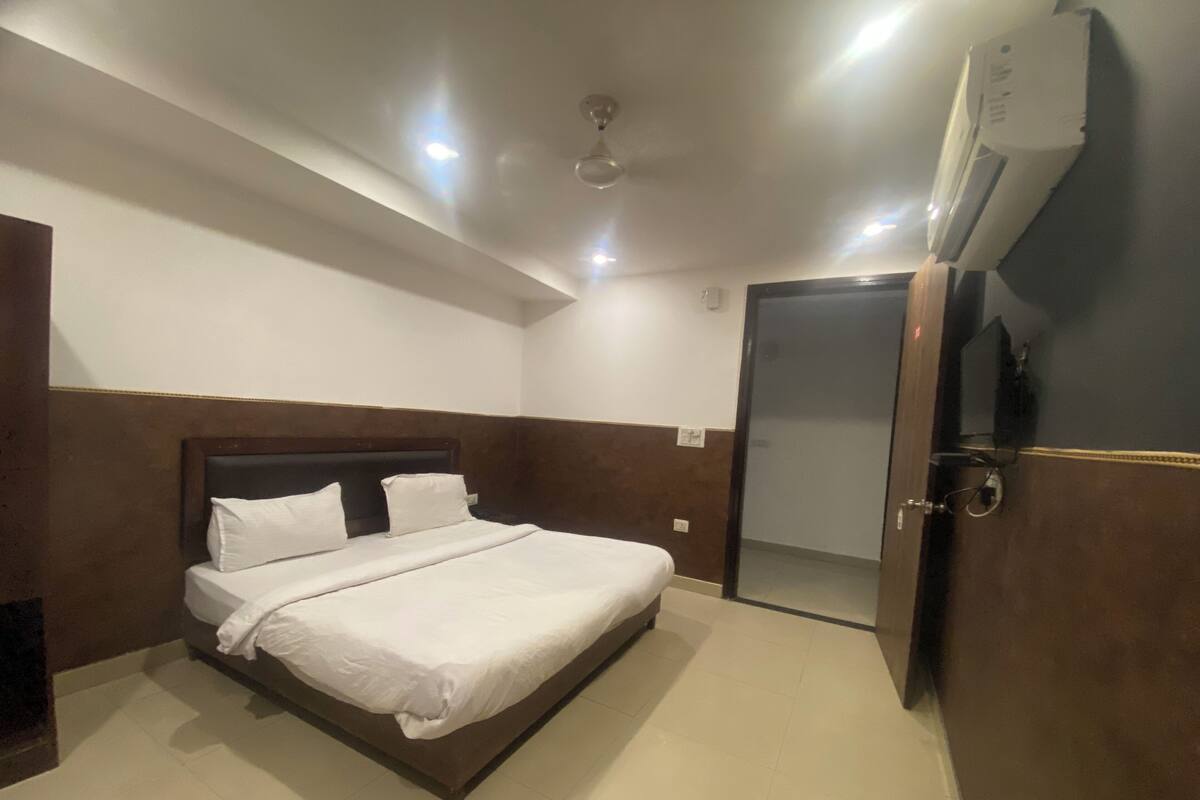Une chambre d’hôtel équipée d’un lit, d’un ventilateur de plafond, d’un appareil de climatisation et d’une porte donnant sur une autre pièce.